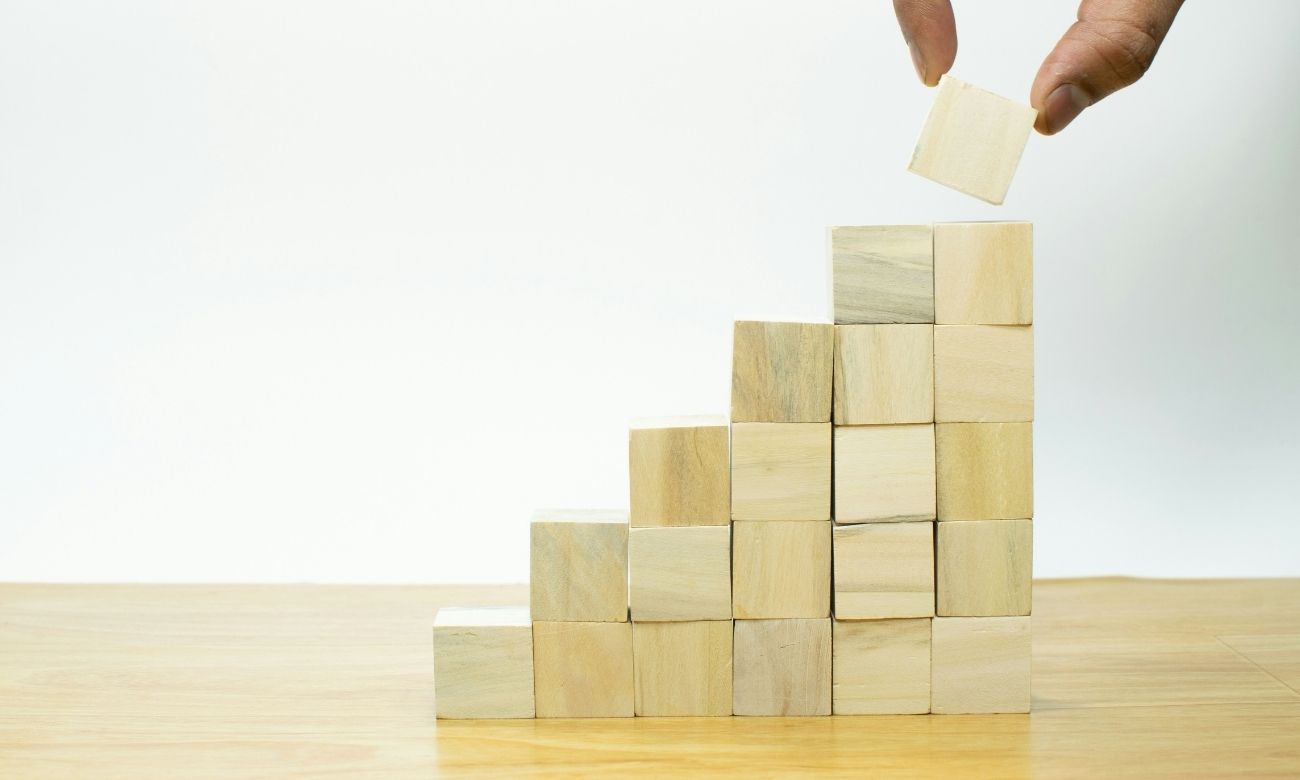Person stacking wooden blocks in the shape of an upward line