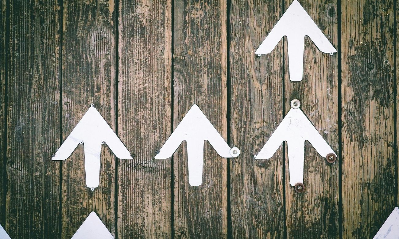 White arrows point up on wooden background
